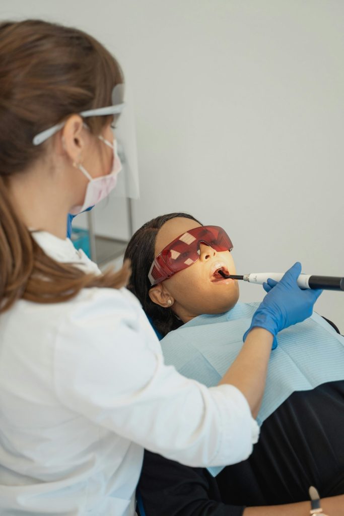 Un dentista utiliza una lámpara de fotocurado en un paciente en una clínica moderna. Atención dental profesional en curso.